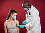 African american doctor giving covid vaccine to mixed race woman and wearing surgical face mask. Hispanic patient getting corona injection from physician against red studio background with copyspace