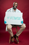 African american covid doctor holding and showing poster. Full length portrait of smiling black physician isolated against red studio background with copyspace. Man promoting corona vaccine on sign