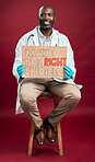 African american covid doctor holding and showing poster. Full length portrait of smiling black physician isolated against red studio background with copyspace. Man promoting corona vaccine on sign