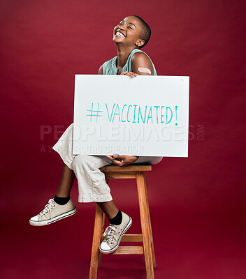 Buy stock photo Poster, smile and vaccine with black woman in studio isolated on red background for healthcare or medical. Chair, hashtag and plaster with patient holding sign for covid awareness or prevention