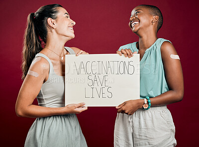 Buy stock photo Laughing, poster and vaccine with happy friends in studio on red background for healthcare or medical. Covid, plaster and vaccination saves lives sign with people together for support or wellness