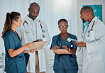 Group of diverse doctors having a meeting together working at a hospital. Team of serious medical professionals talking while planning their day at work at a clinic