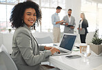 Portrait of a young mixed race businesswoman working on a laptop at work. Happy hispanic female businessperson with a curly afro typing en email on a laptop in an office