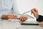 Closeup of two businesspeople working on a digital tablet in a meeting together at work. Business professionals using technology in an office. Boss showing an employee an idea on a digital tablet