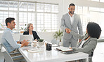 Diverse group of businesspeople having a meeting together at a table at work. Business professionals talking and planning while using technology in an office. Hispanic businessman greeting a mixed race businesswoman with a handshake