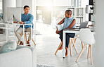 Two businesspeople talking while working in an office together. Young asian businessman talking to an african american businesswoman at work. Colleagues talking on a break