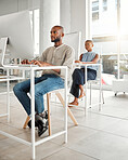 Young serious african american businessman using a desktop computer in an office at work. Focused male businessperson typing an email at a desk. Business professional working on a computer