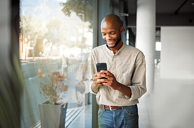 Buy stock photo Happy, black man or typing with phone by window for communication, online chat or app at office. Young African, male person or salesman texting on mobile smartphone for business proposal at workplace