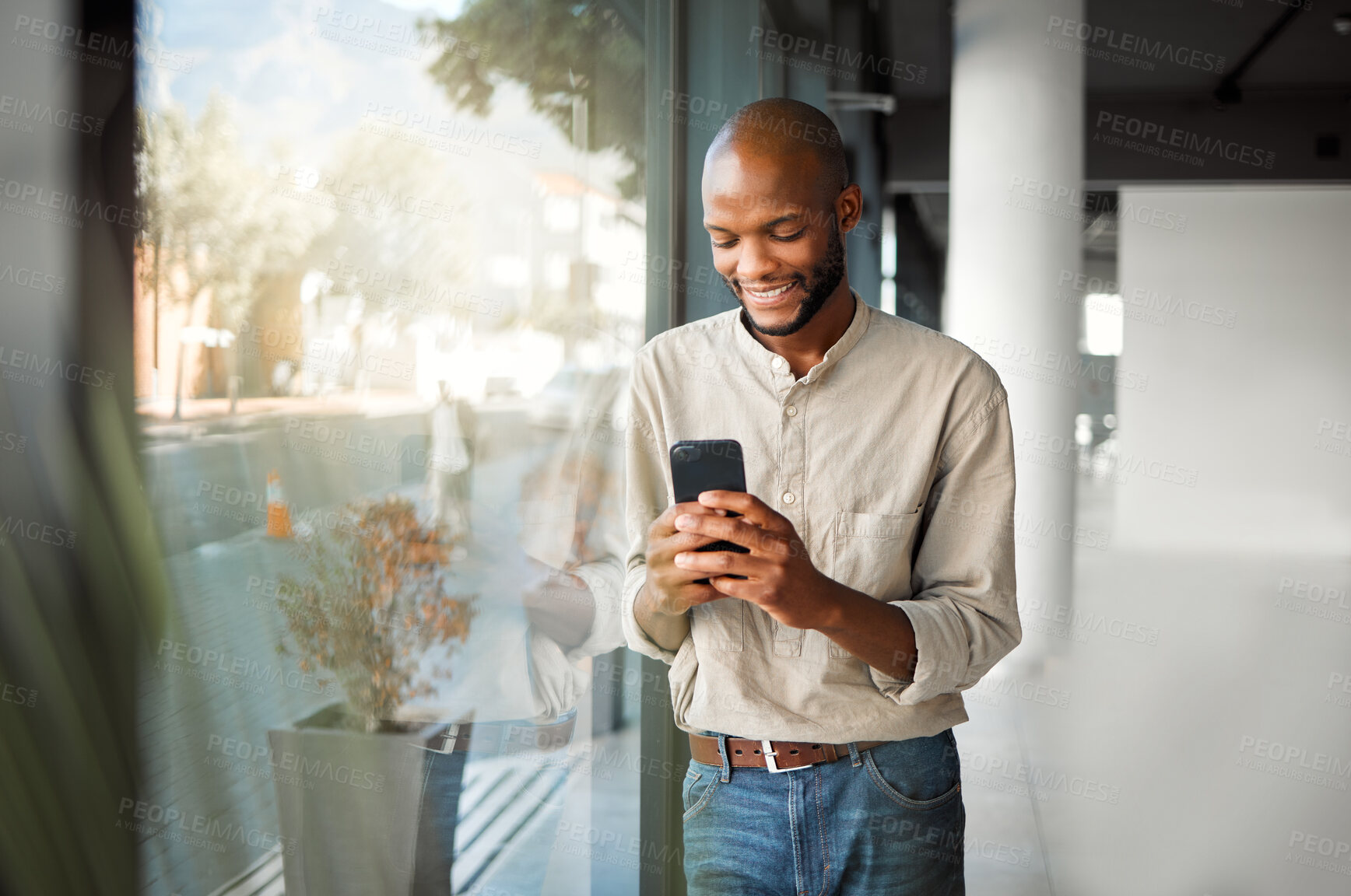 Buy stock photo Happy, black man or typing with phone by window for communication, online chat or app at office. Young African, male person or salesman texting on mobile smartphone for business proposal at workplace