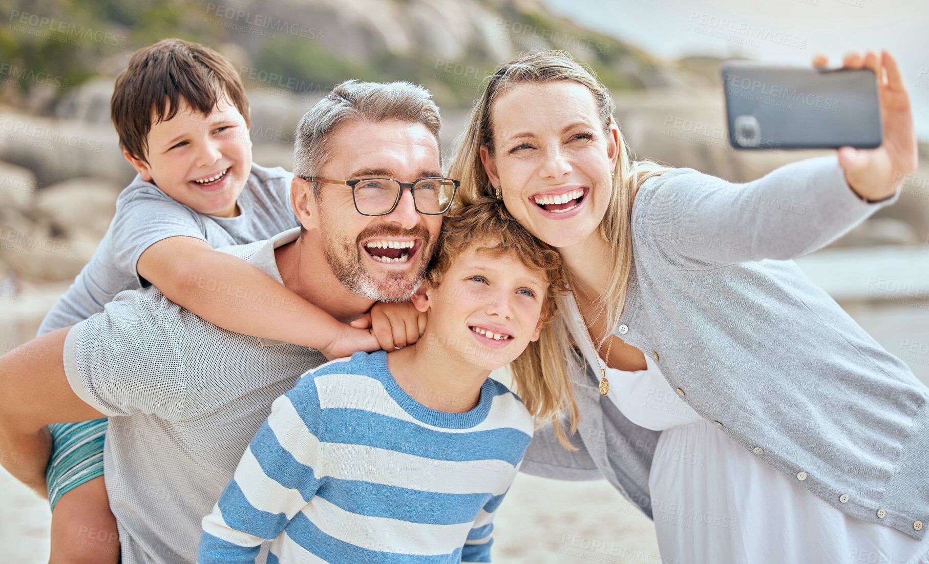 Buy stock photo Parents, children and selfie at beach with smile, excited and bonding for love on vacation in summer. Father, mother and kids on holiday for memory, embrace or social media for piggy back in sunshine