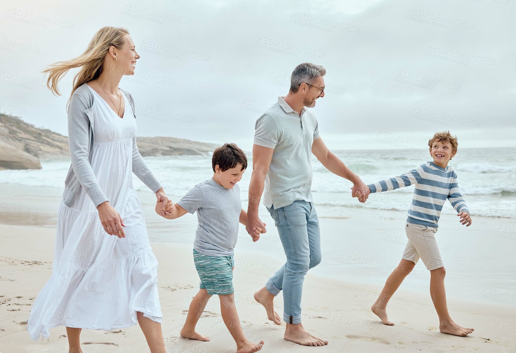 Buy stock photo Parents, kids and holding hands at beach with smile, walk or bonding with love on vacation in summer. Father, mother and children on holiday for connection, memory or talking with family in sunshine