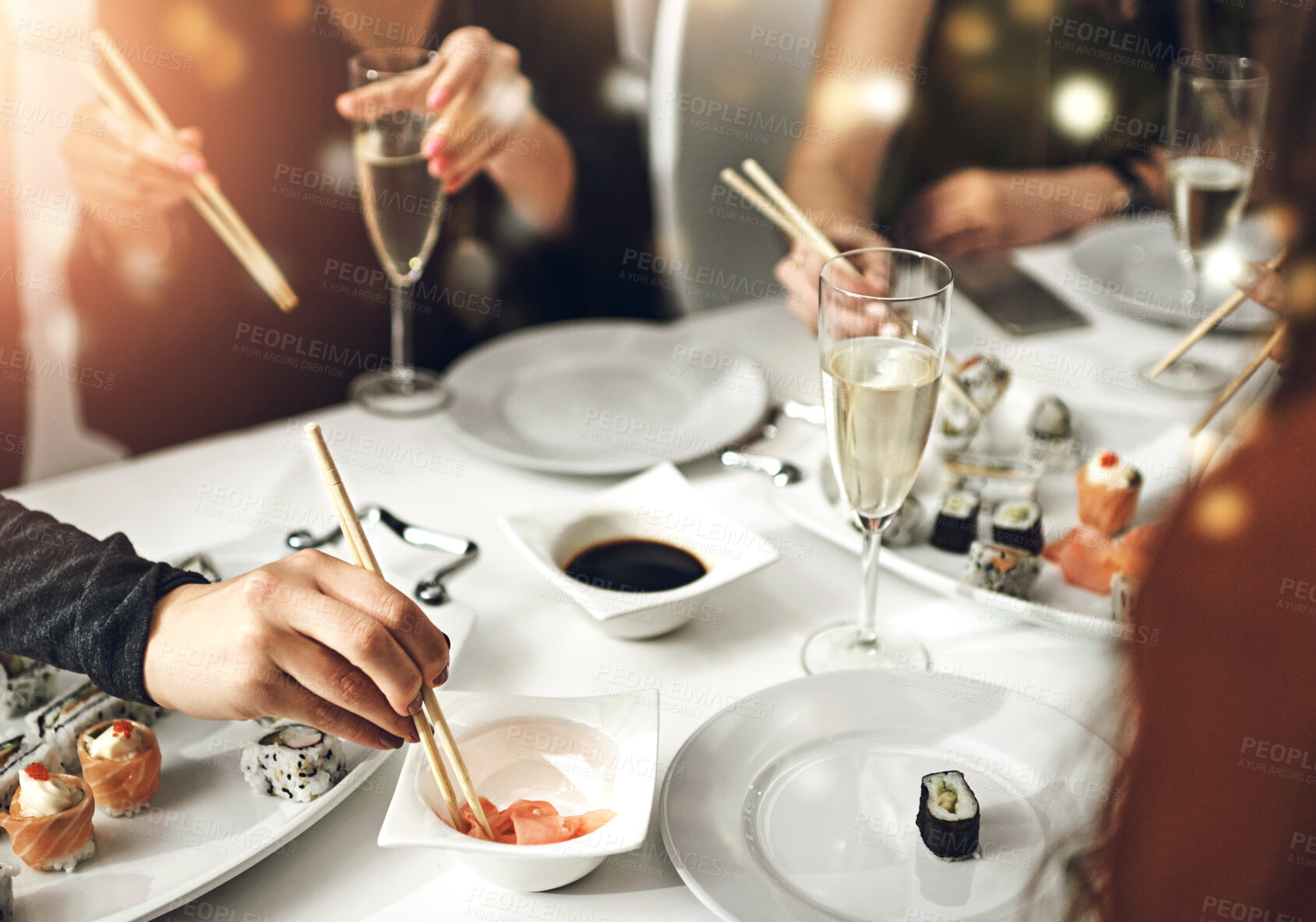 Buy stock photo Hands, friends and sushi in restaurant for lunch, social gathering and sharing at table. People, Japanese cuisine and champagne for fine dining with luxury food, birthday celebration or girls bonding