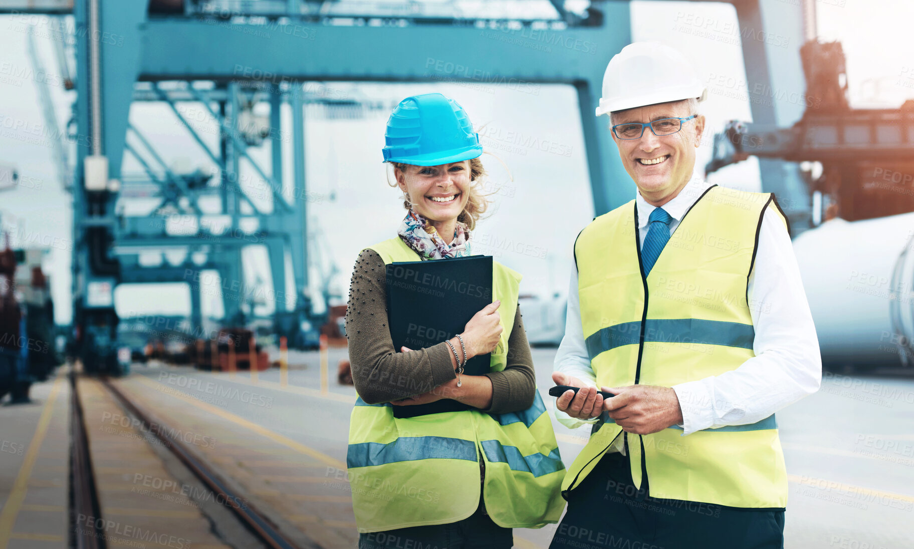 Buy stock photo Mature man, woman and logistics at port in portrait, smile or helmet by rail for supply chain management. People, happy and mentorship at harbor with cargo, distribution and storage in Portugal