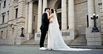 Couple, hug and kiss on wedding outdoor with promise, celebration and marriage commitment. People, embrace and love with affection for partnership, relationship loyalty and romance ceremony at court