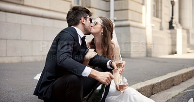 Buy stock photo Wedding, kiss and couple in city with alcohol for ceremony, celebration or commitment with embrace. Romance, love and man and woman in town with champagne for promise, affection and marriage at court