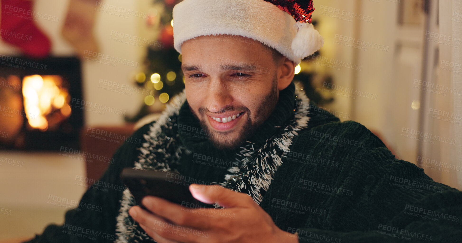 Buy stock photo Happy, man and relax with phone on Christmas for social media, update and online post at home. Santa hat, smile and male person with technology in living room for celebration, chat or festive message