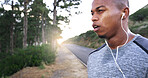 Man, runner and earphones in road, outdoor and perspective with music, break and fitness training in summer. African person, reflection and streaming for exercise, workout or sound by forest in Kenya