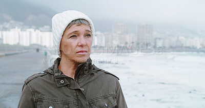 Buy stock photo Sad, beach and mature woman with thinking, grief and loss outdoor with depression and mental health. Lonely, sea and winter vacation with travel, memory and bad news by ocean to remember the past