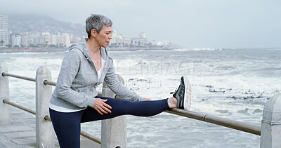 Buy stock photo Senior woman, stretching and fitness at beach with peace, leg flexibility or running preparation. Retired athlete, warm up or muscle tension relief at seaside for exercise, wellness or care in Italy