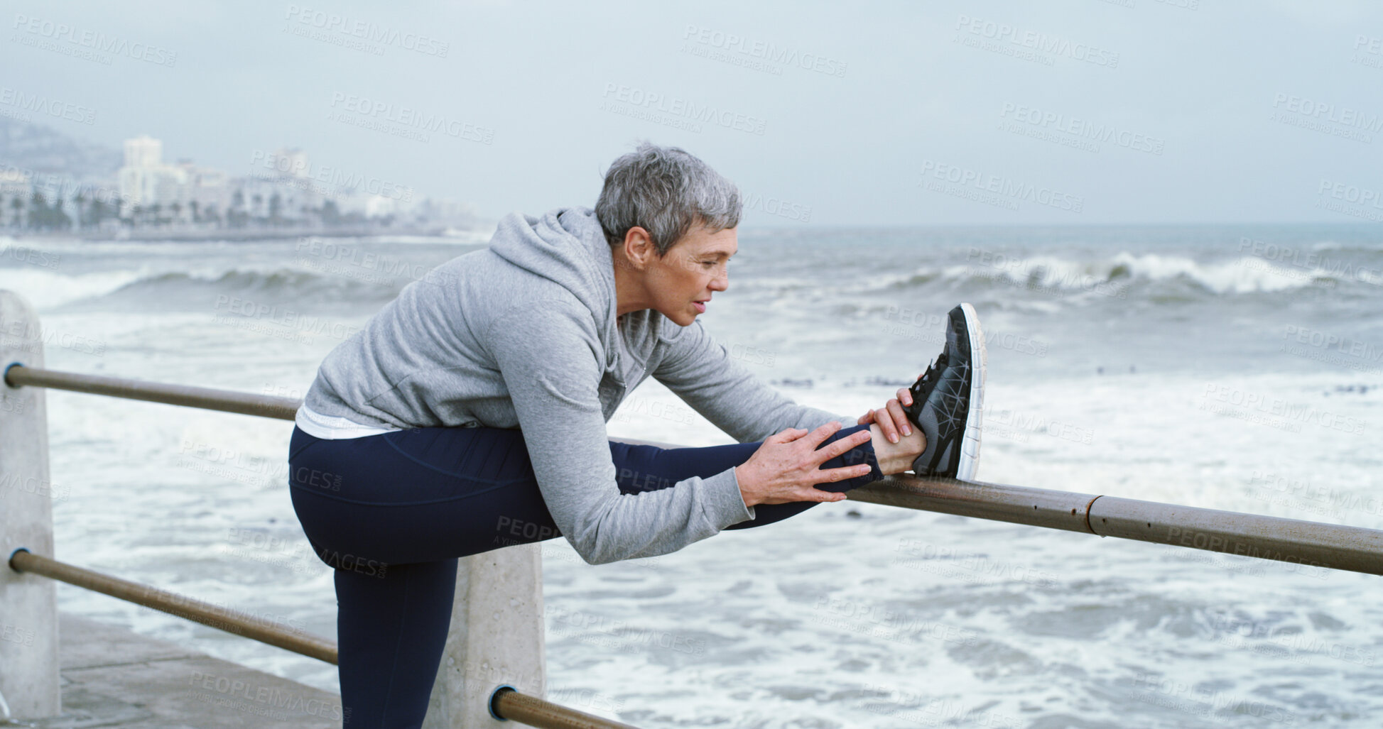 Buy stock photo Mature person, stretching legs and fitness at ocean with peace, flexibility or running preparation. Woman athlete, warm up or muscle tension relief at seaside for exercise, wellness or care in Italy