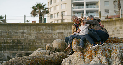 Buy stock photo Grandparents, grandchild and relax on rocks at beach for family holiday, happy memory and travel adventure. Senior people, boy child and playing together for connection, bonding or trust by coastline