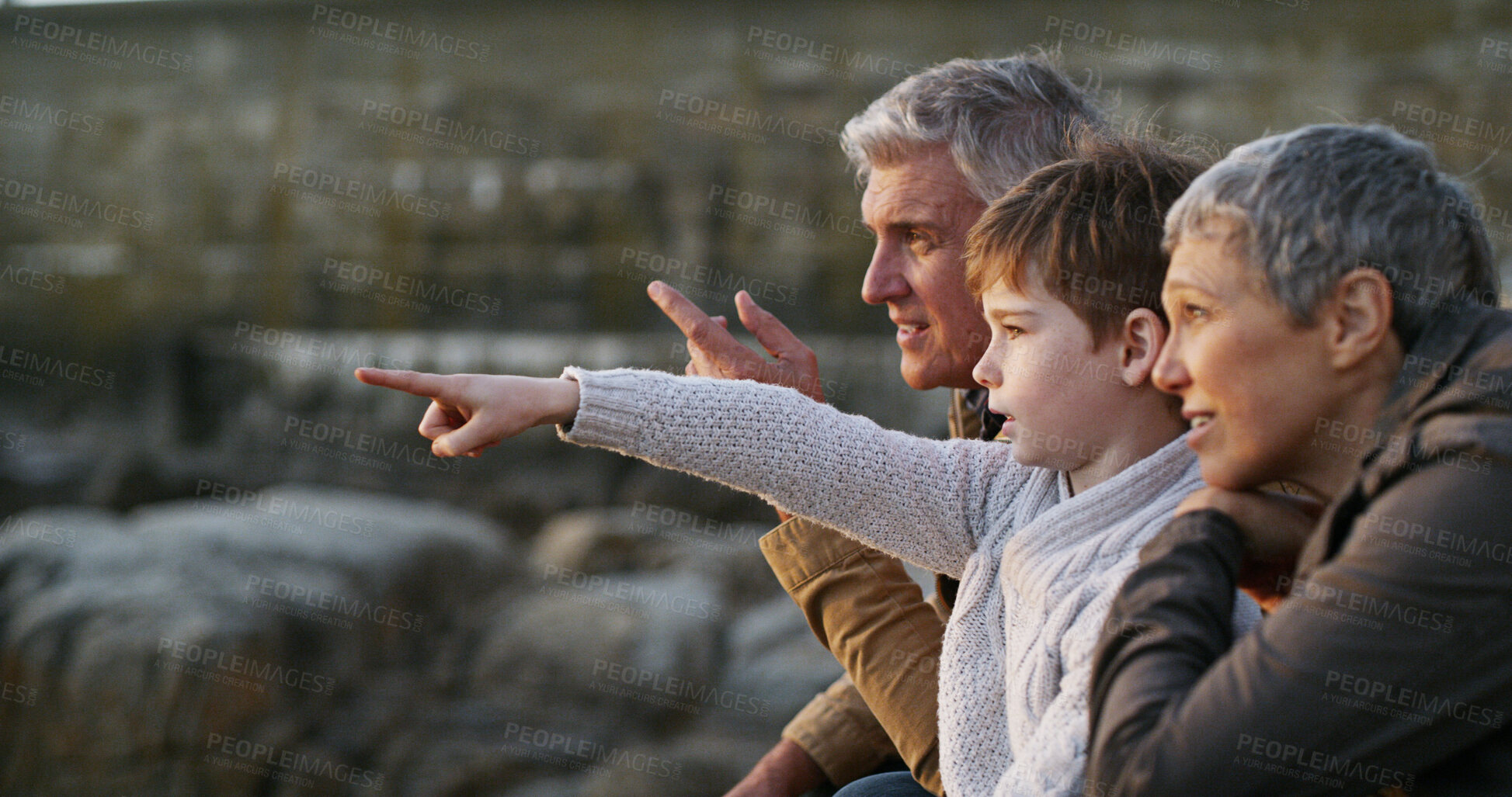 Buy stock photo Grandparents, grandchild and pointing on beach, outdoor and seashore for bonding together. Senior people, boy and weekend for sightseeing, ocean and vacation on winter holiday with family for support