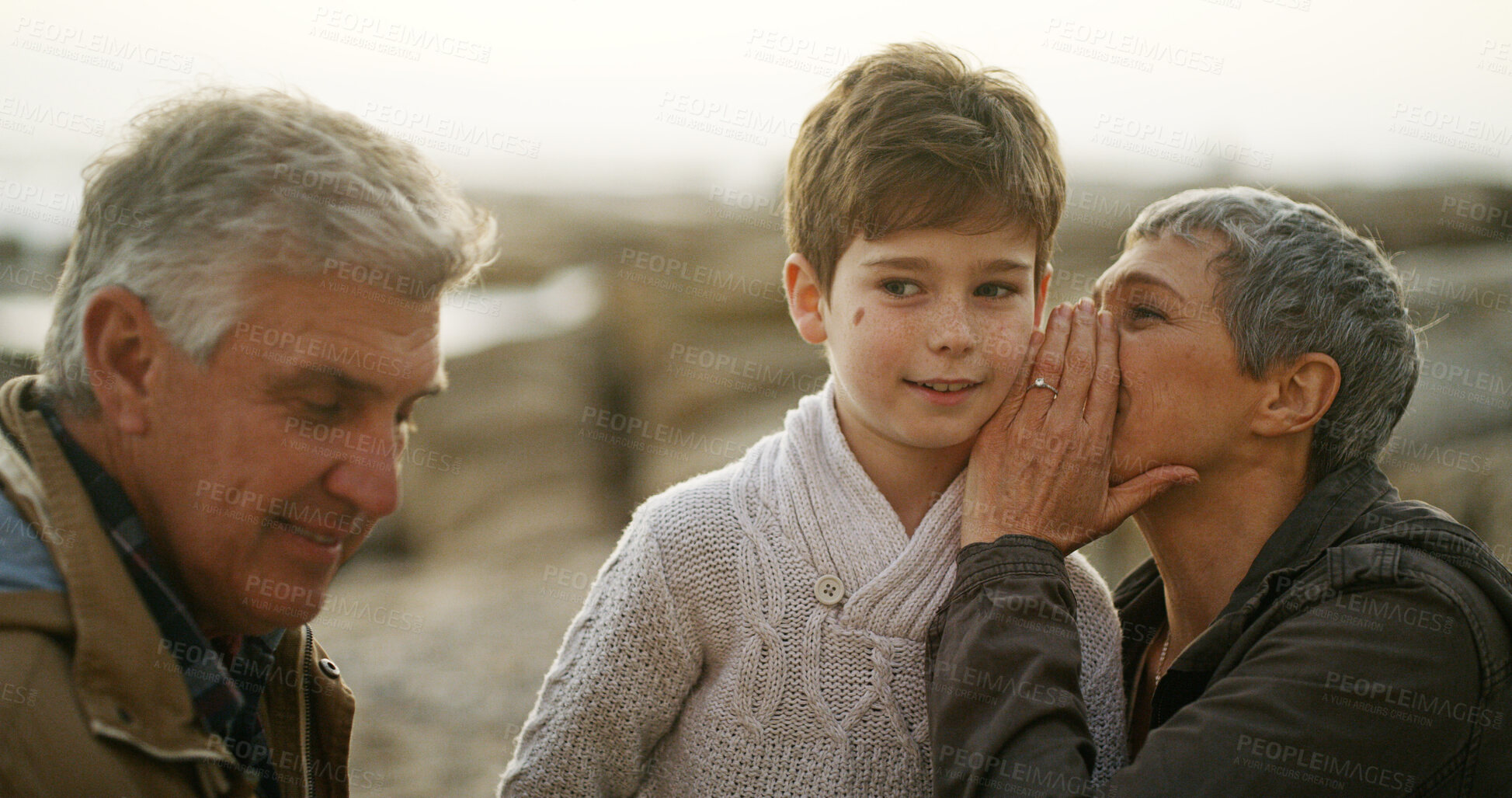 Buy stock photo Grandparents, grandchild and whisper for bonding together on beach, outdoor and seashore. Senior people, boy and weekend for secret, childcare and vacation on winter holiday with family for support