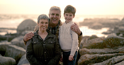 Buy stock photo Happy, sea and portrait of grandparents with child for bonding, fun weekend and relax together at beach. Rocks, family and young boy, grandpa and grandma on holiday, adventure or vacation at sunrise
