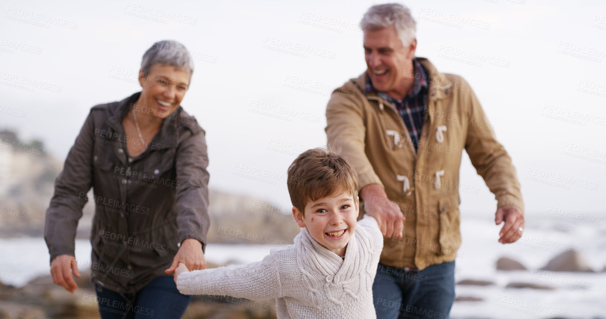 Buy stock photo Grandparents, grandchild and walking on beach, outdoor and seashore for bonding together. Senior people, boy and weekend for holding hands, care and vacation on winter holiday with family for support