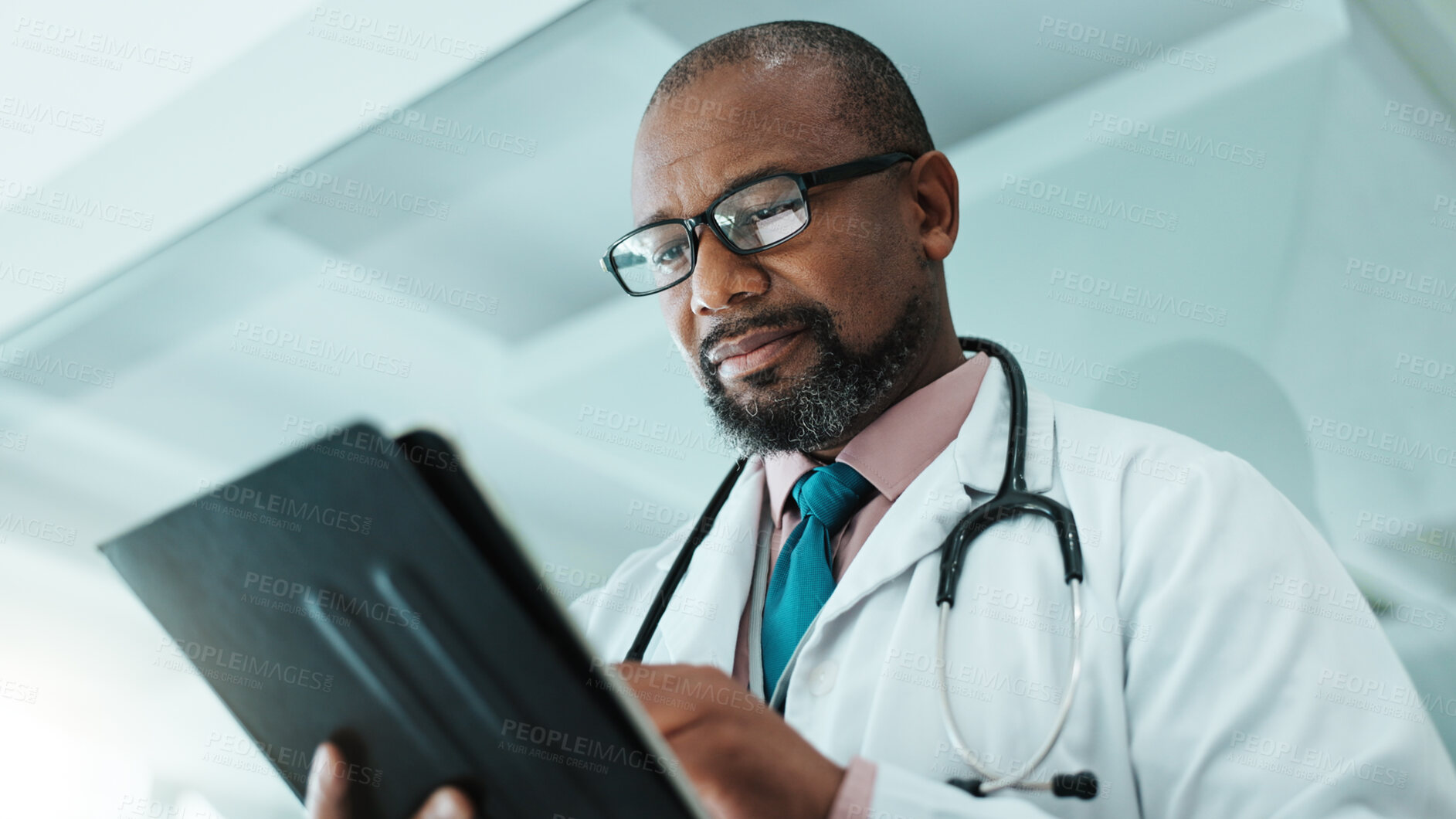 Buy stock photo Black man, doctor and tablet for medical in hospital with healthcare research, Telehealth and surgery schedule. Male surgeon, reading and digital for history report, patient information and diagnosis