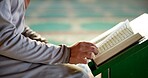 Muslim person, hands or arabic with quran on stand at mosque for recitation, praying or dua in temple. Islam, closeup or arab with islamic testament, holy scripture or faith in belief for word of god