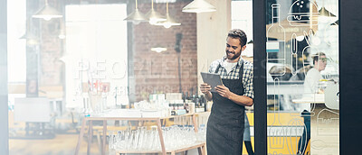 Buy stock photo Shot of a young man using a digital tablet in the store that he works at