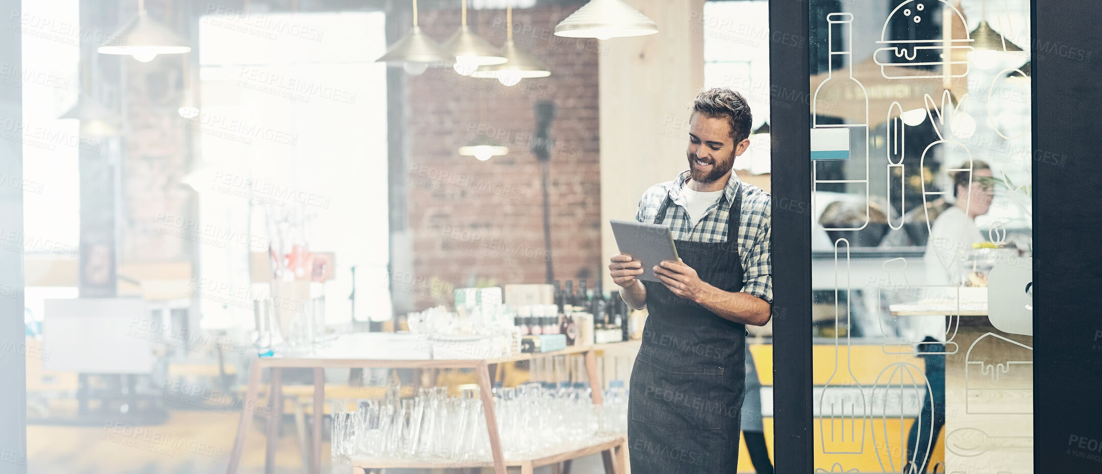 Buy stock photo Shot of a young man using a digital tablet in the store that he works at