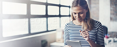 Buy stock photo Shot of a young designer using her digital tablet in her office