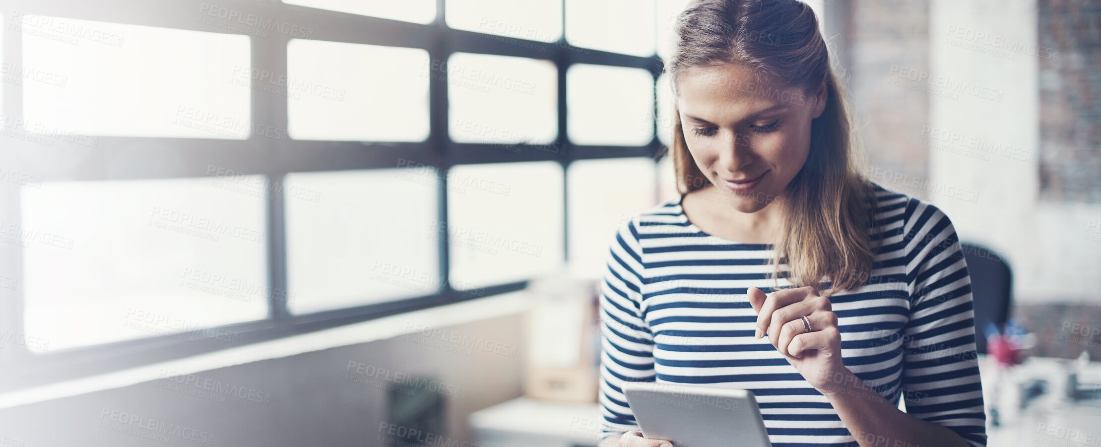 Buy stock photo Shot of a young designer using her digital tablet in her office