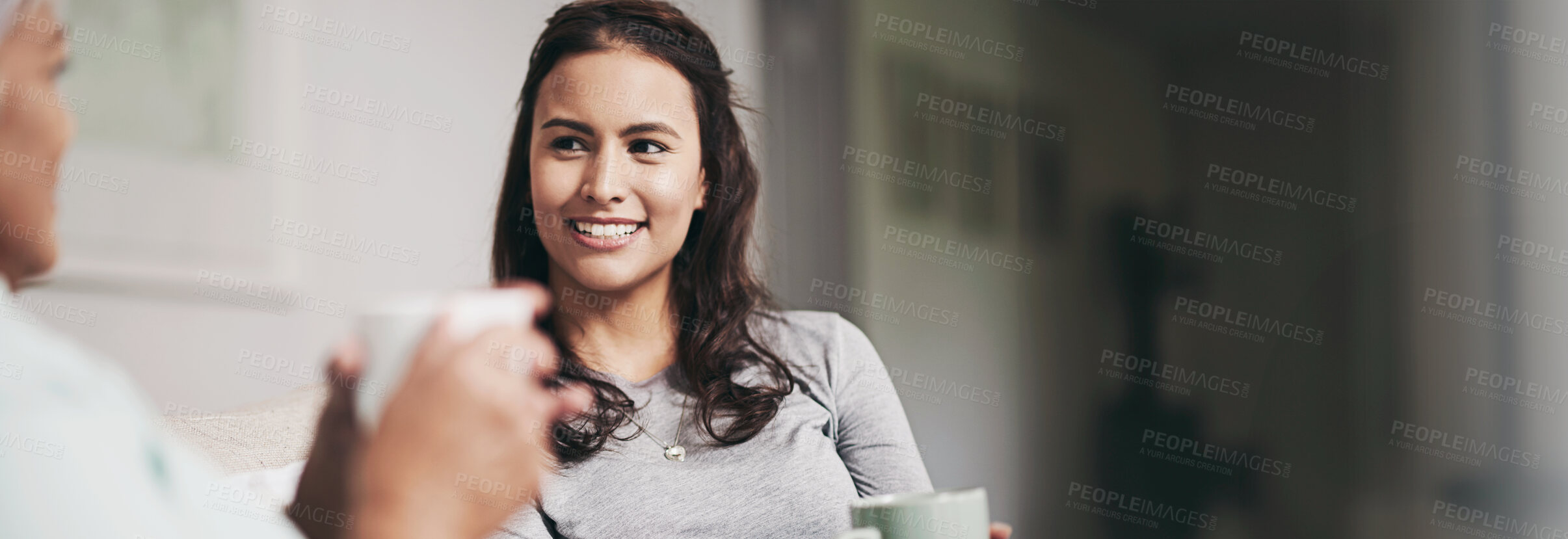 Buy stock photo Shot of a young woman and her mother catching up on the sofa while drinking coffee