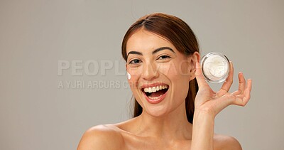 Buy stock photo Portrait, smile and woman with cream, shine and dermatology on gray studio background. Person, happy model and girl with skincare, cosmetics and container for creme, healthy skin and grooming routine