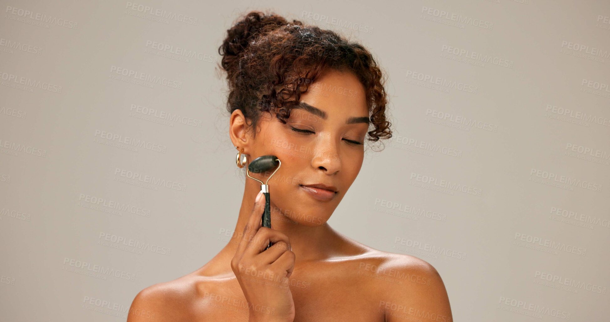 Buy stock photo Studio, woman and eyes closed with roller for skincare on portrait for facial, beauty and firm skin on gray background. Female person, beautician and confidence with stone massage, cosmetics and glow