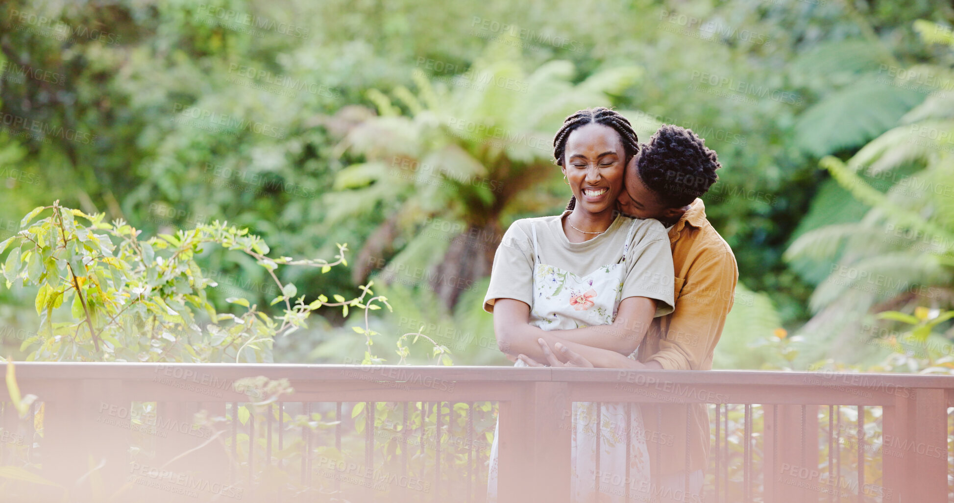 Buy stock photo Kiss, hug and black couple on bridge in park for bonding, love connection and outdoor adventure. Commitment, man and woman on path in nature for romantic date, weekend embrace and happy green garden.