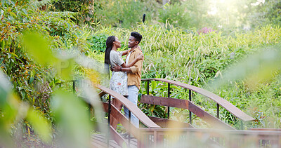 Buy stock photo Love, hug and black couple on bridge in park for bonding, connection and outdoor adventure together. Commitment, man and woman on path in nature for romantic date, weekend embrace and green garden.