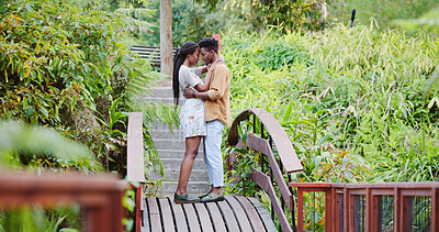 Buy stock photo Love, embrace and black couple on bridge in park for bonding, connection and outdoor adventure. Commitment, man and woman on path in nature for romantic date, weekend hug and trust in green garden.