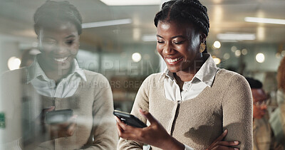 Buy stock photo Woman, smartphone and texting by window, office and chat at night with reflection, contact or networking at company. African person, happy and phone for deal, overtime or reading at creative agency