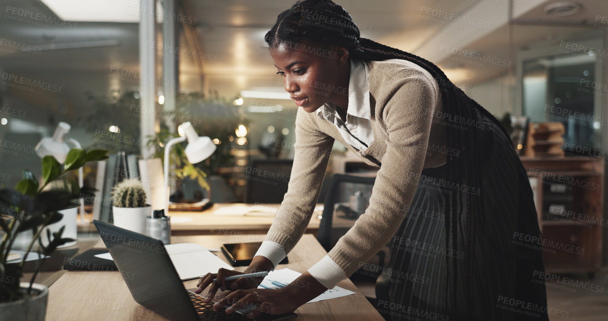 Buy stock photo Black woman, laptop and typing at night in office for project, review or deadline at media company. African person, writer and computer for feedback, overtime and editing article at creative agency