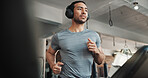 Man, headphones and workout on treadmill at gym for running, training and cardio exercise. Fitness, athlete and listening to music or radio app on machine for marathon endurance and speed challenge