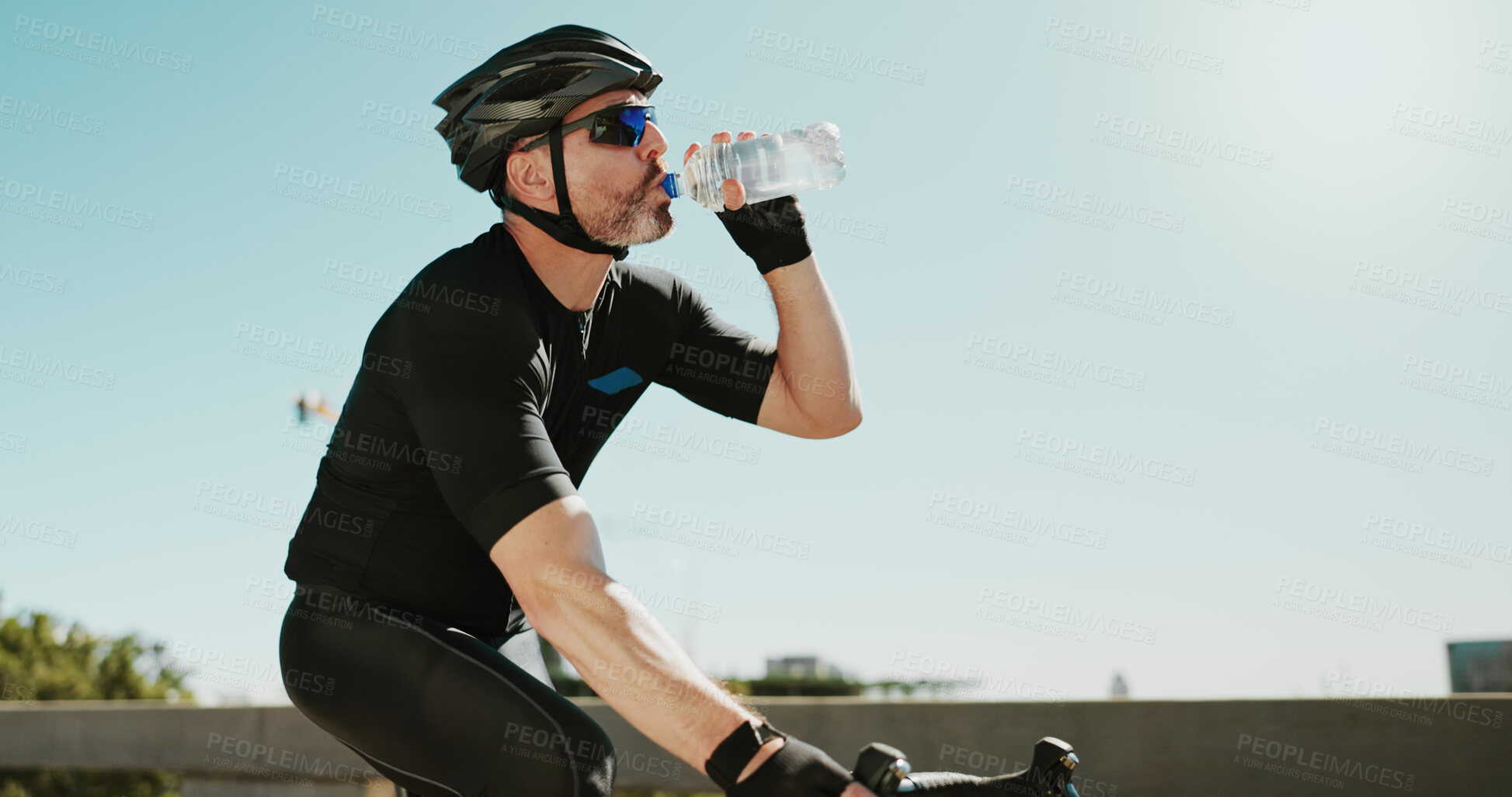 Buy stock photo Drinking water, fitness and cycling with man in city for triathlon challenge, electrolytes and workout. Wellness, exercise and competition with person and bike for sports, training and mockup space