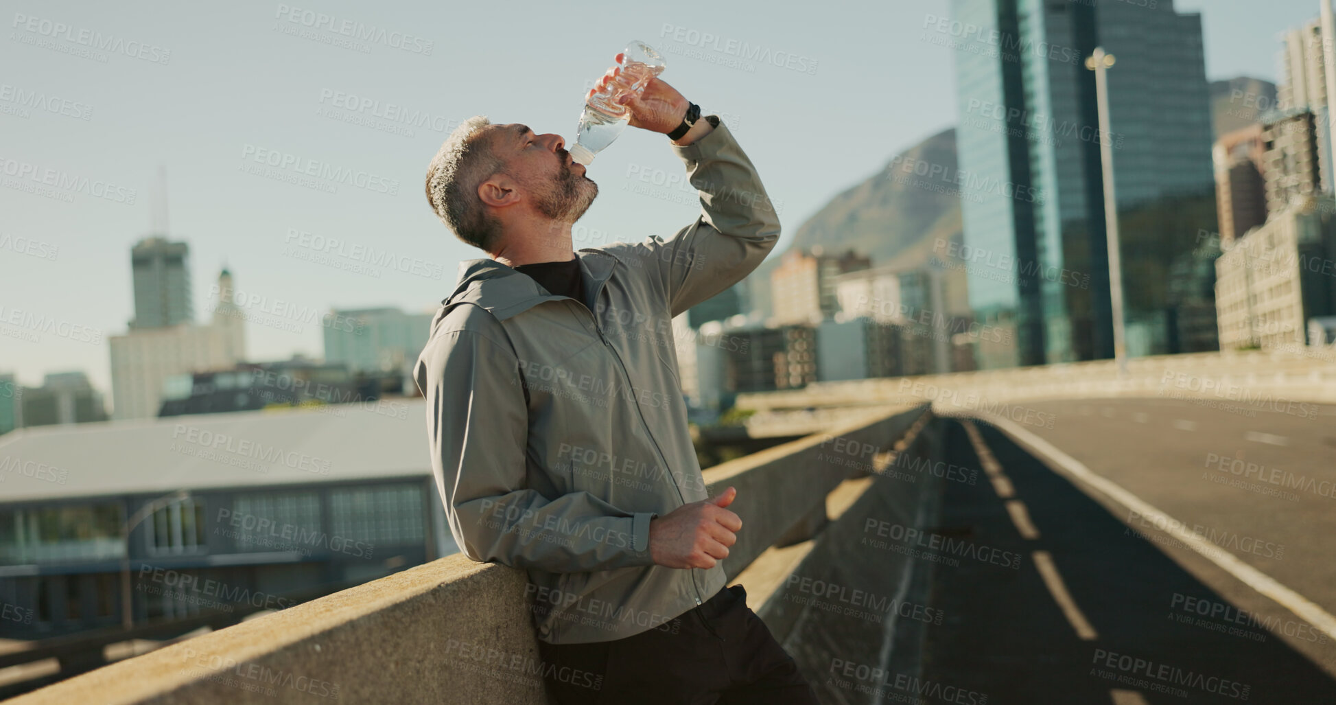 Buy stock photo Fitness, drinking water and man in city for wellness, health and hydration in town for running. Sports, morning and person with liquid, minerals and bottle for marathon training, workout and exercise