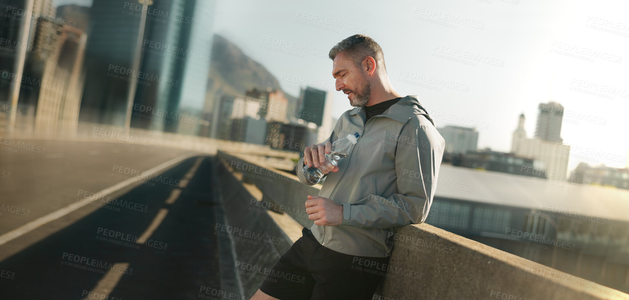 Buy stock photo Fitness, man and tired in city with time, check active heart rate or catch breath in Italy. Mature athlete, fatigue or rest on bridge for exercise, thirsty or cardio app for progress tracking on road