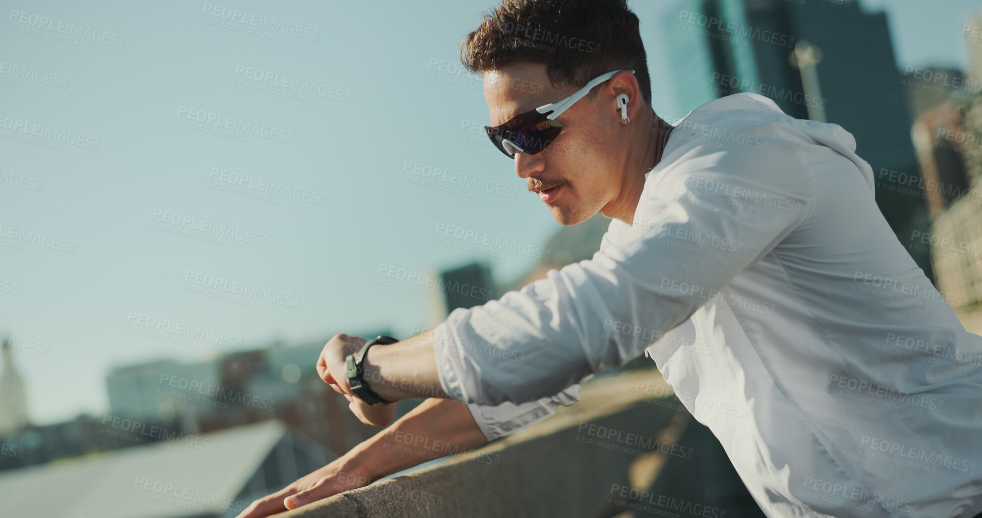 Buy stock photo Man, time and fitness in city on break, thinking and check smart watch for exercise progress. Earphones, bridge and tired runner outdoor for health, wellness and listening to podcast for training