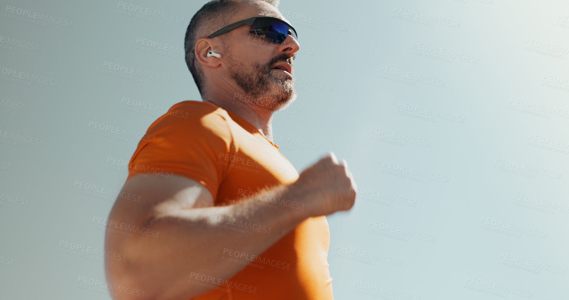 Buy stock photo Man, sky and running with earphones for exercise, streaming music and sunglasses for cardio. Male person, mockup space and athlete for sports workout, hearing audio and outdoor for fitness activity