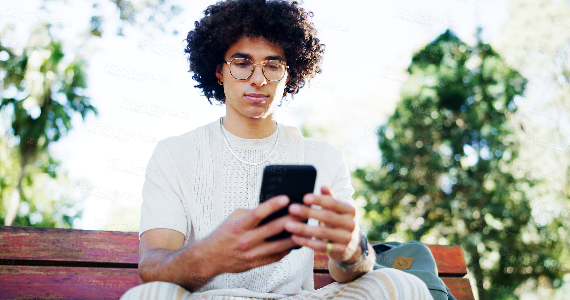 Buy stock photo Man, student and smartphone with texting on park bench, reading and break with mobile app in summer. Person, phone and scroll at college with chat, contact and social network at campus in Costa Rica